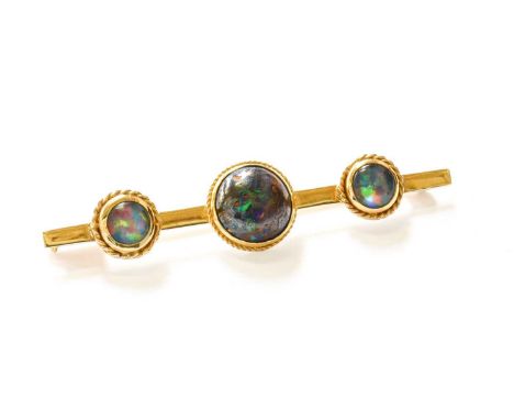 An Opal and Opal Doublet Brooch, the graduated round cabochon opals in yellow rope twist borders laid upon a plain polished b