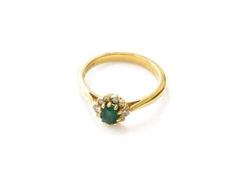 An 18 Carat Gold Emerald and Diamond Cluster Ring, the oval cut emerald within a border of round brilliant cut diamonds, in y