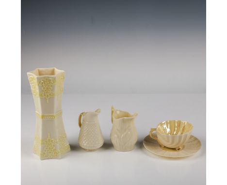 An eclectic collection of cream colored Belleek porcelain items including a cup and saucer in the sea shell design, two handl