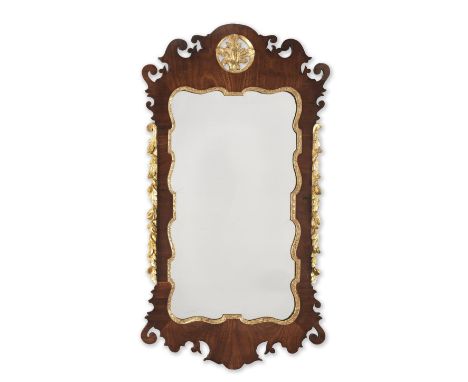A GEORGE II MAHOGANY AND PARCEL GILT WALL MIRRORThe shaped later plate within a foliate slip and scroll-cut frame, the cresti