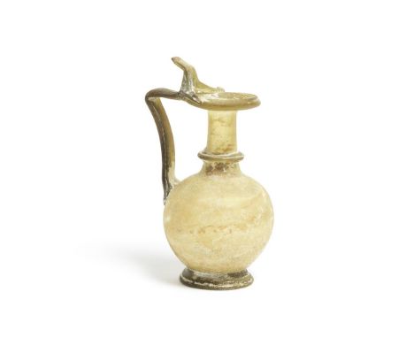 A ROMAN YELLOW-GREEN GLASS JUG Circa 3rd-4th Century A.D.The body of globular form with flared rim, the cylindrical neck wit