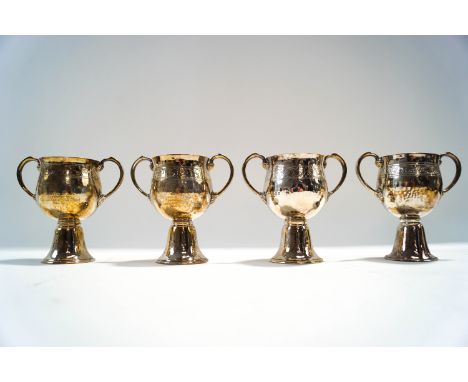 A matched set of four silver hammered two handled cups, by Goldsmiths & Silversmiths Co Ltd, London 1934, 1935, 1936, and 193