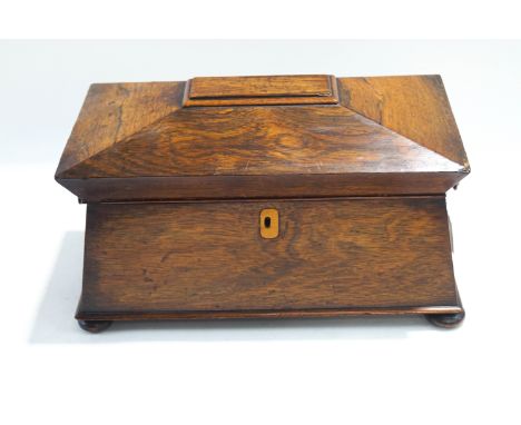 A 19th century rosewood tea caddy of sarcophagus form, the interior with two lidded compartments, turned handles and bun feet