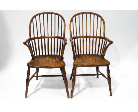 A pair of 19th century beech and elm comb back Windsor chairs, each with a saddle seat, 101cm high (replacement stretchers)