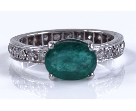 An unmarked white gold diamond set band ring with central oval emerald, emerald 8.5mm across, size M.