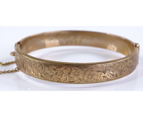A 9ct gold hinged bangle with floral engraved front, internal diameter 59.3mm, 13.9g