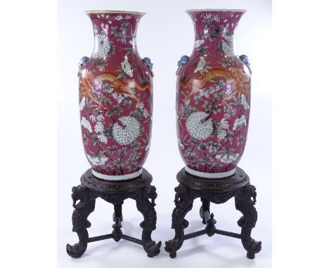 A pair of Chinese porcelain vases, hand painted enamel dragon and prunus flower designs, height 44cm, on carved hardwood stan