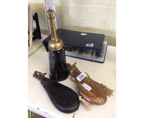 A copper shot flask together with a leather shot flask and a horn and brass shot flask.