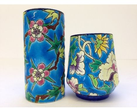 A Longwy small enamel decorated cylindrical spill vase together with a small Longwy vase, decorated with flowers.