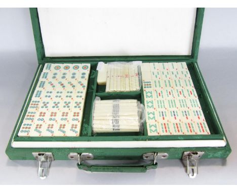 A mahjong game with bone and bamboo tiles in a green silk lined carry case. 