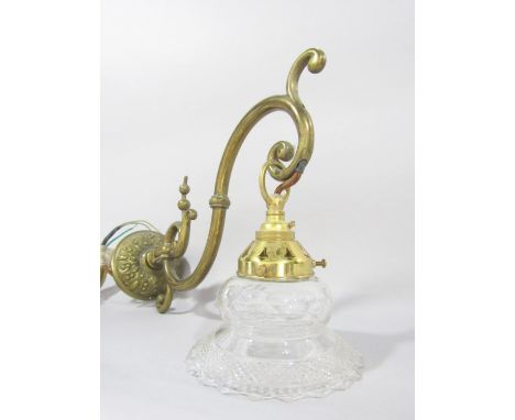 A brass scrolled wall light with a dangling glass shade, and a section of another brass light fitting. 