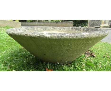 A weathered cast composition stone planter of squat conical form 78 cm diameter x 30 cm high 