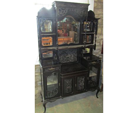 An Edwardian ebonised chiffonier of full height, the lower section enclosed by a series of doors and drawers with carved deta
