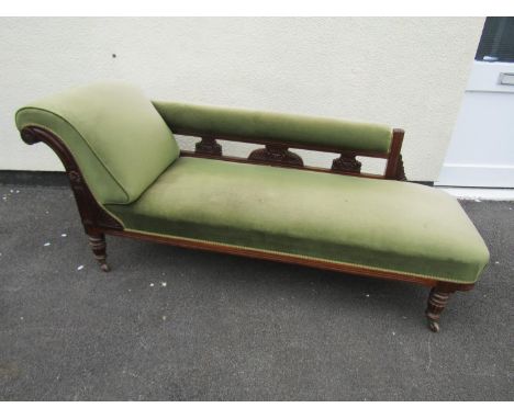 A late 19th century mahogany chaise lounge with carved detail and green dralon upholstered finish, together with a lamp stand