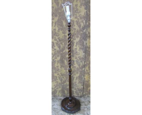 An Edwardian oak lamp standard with barley twist supports raised on a disk shaped base 