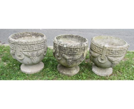 A set of three weathered cast  composition stone circular garden urns with repeating Greek key, fixed ring and further detail