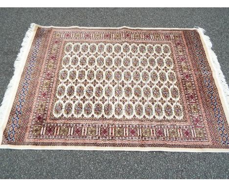 A Bokhara carpet on a beige ground measuring 190 cm x 133 cm, (nominal use, no marks)