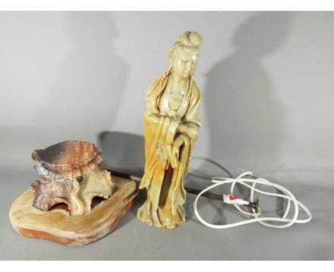A Chinese soapstone carving depicting Guanyin in standing pose atop a lotus dais, wearing flowing robes and holding a scroll,
