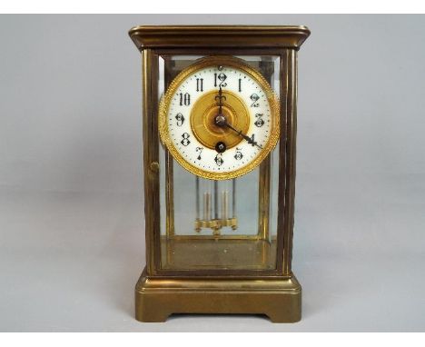 A timepiece only, four-glass and brass mantel clock, the dial having enamel chapter ring, Arabic numerals and pressed brass c