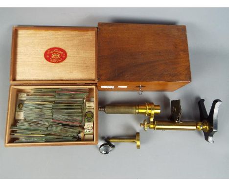 A boxed, vintage brass microscope and a large quantity of slides. [2]