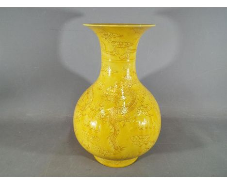 A large Chinese yellow glazed baluster vase with everted rim, decorated with incised phoenix above dragons chasing the flamin