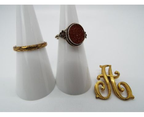 Goldstone - a white metal ring set with flat oval Goldstone, measuring 1 cm x 0.8 cm, ring unmarked presumed silver, size K, 
