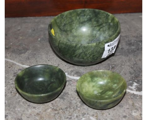 A green hard stone bowl together with two similar smaller bowls, probably Chinese jade. (3)