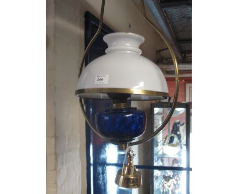 Hanging brass oil lamp burner with blue glass reservoir and cream shade. 