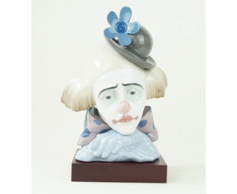 A Lladro ceramic figural bust Depicting a clown, model number 5130, printed factory marks to base, raised on wooden plinth ba