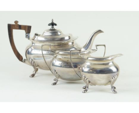 A George V silver matched three piece tea serviceOf ovoid form, wavy rims, angular handles, raised on four shell capped feet,