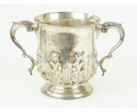 A Victorian silver two handled trophyOf circular form, the lower body embossed Art Nouveau leaf detail, with leaf capped scro