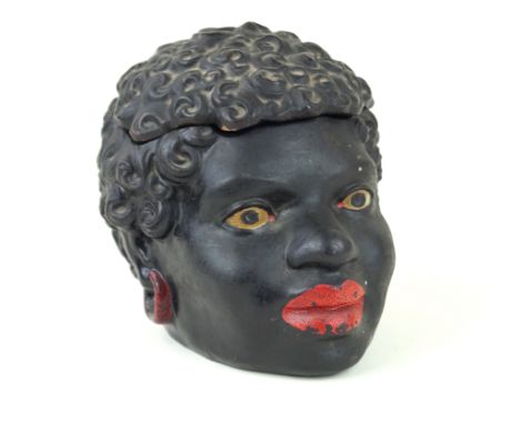 A continental painted ceramic tobacco jarModelled in the form of a black woman's head with detachable cover, impressed U&G to