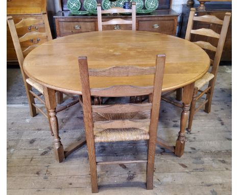 A Nigel Griffiths English oak circular gate leg drop leaf dining table with four matching rush seated farmhouse kitchen chair