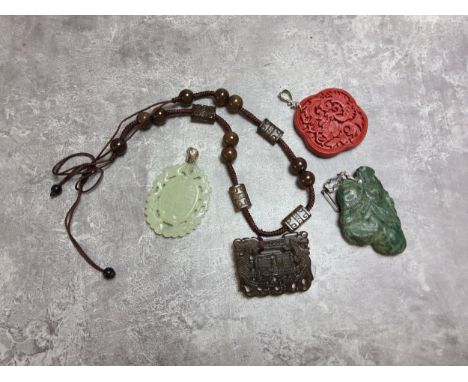 An unusual jadeite carved amulet of indistinct form; a pale nephrite amulet etc. (4) 