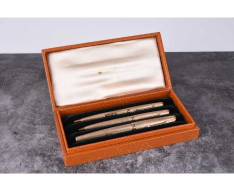 A cased three piece 9ct gold Parker pen set, comprising; a fountain pen, ball point pen and propelling pencil, each with engi