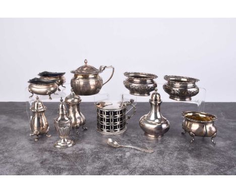 A collection of silver cruets, comprising; a pierced drum mustard with blue glass liner, a pair of oval salts with embossed b