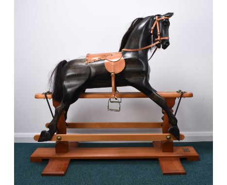 A large Deborah Fownes carved wood rocking horseStained dark grey with brown mane and tail, faux tan leather saddle, bridle a