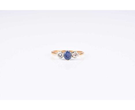A graduated three stone sapphire and diamond ring, designed as a central round mixed cut sapphire claw set in white metal bet