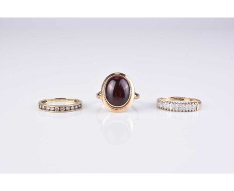 Three 9ct gold stone set rings, comprising; a cabochon garnet example, size L, a diamond set example, size I and a cubic zirc