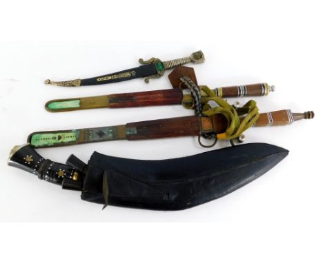 A kukri, with curved blade and horn handles and leather scabbard, with two small accompanying knives, a decorative Middle Eas