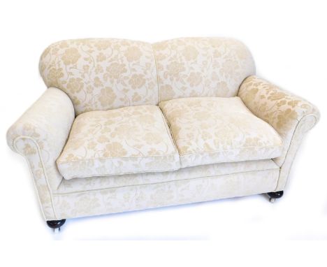 An Edwardian two seater sofa, re-upholstered in floral fabric, on bun feet.