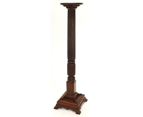 A mahogany torchere or plant stand, with a circular dished top on a part reeded turned leaf and wheat ear carved column, on a