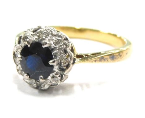 A sapphire and diamond dress ring, set in a floral cluster with circular cut dark sapphire, surrounded by tiny diamonds on a 