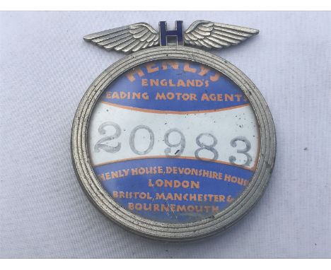 A Henlys, England's Leading Motor Agent tax disc holder surmounted by a blue enamel and winged pediment, with blue enamel bad