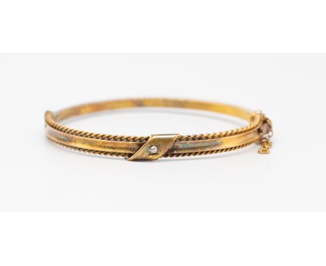 An early 20th century diamond set 15ct gold bangle, comprising a small old cut diamond set to the centre, within a rope twist