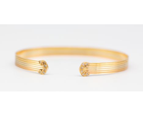 A diamond set three colour 18ct gold torque bangle, comprising diamond set details to the front overlaid to rows of rose, yel