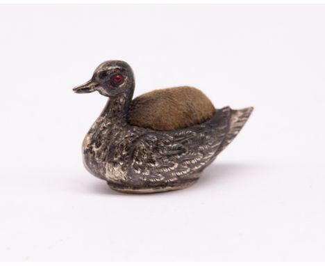 An Edwardian silver novelty pin cushion in the shape of a duck, having ruby glass eyes, hallmarked by Boots pure drug company