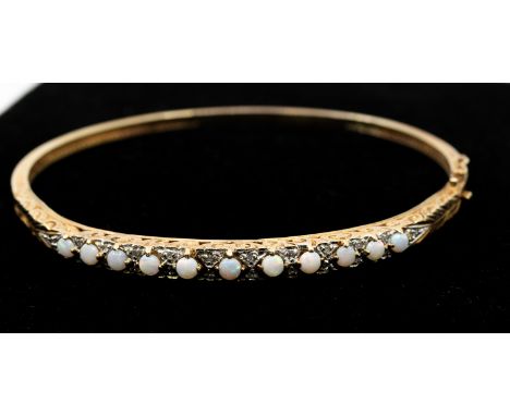 An opal and diamond set 9ct gold bangle, set with round graduated cabochon opals with small diamond set accents, scrolled mou