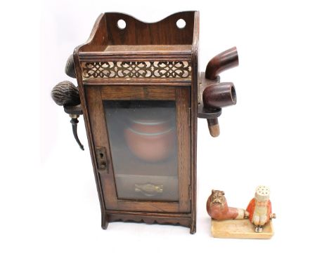 A late Victorian/Edwardian oak smokers cabinet with pierced&nbsp; gallery top side pipe holders, glazed front, single accesso