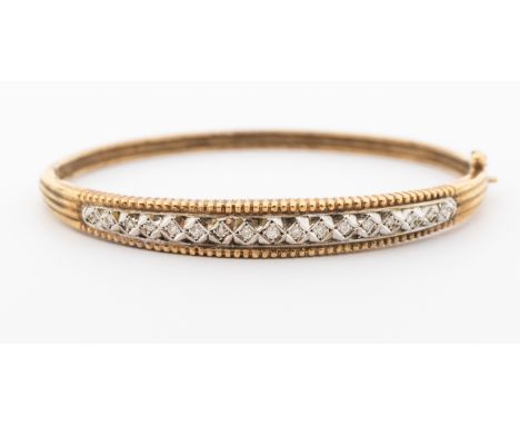 A diamond set 9ct gold bangle, comprising a central row of small illusion set diamond in white gold, ridged  mount, hinged, i